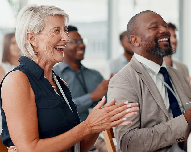 Audience members smiling and applauding at an event